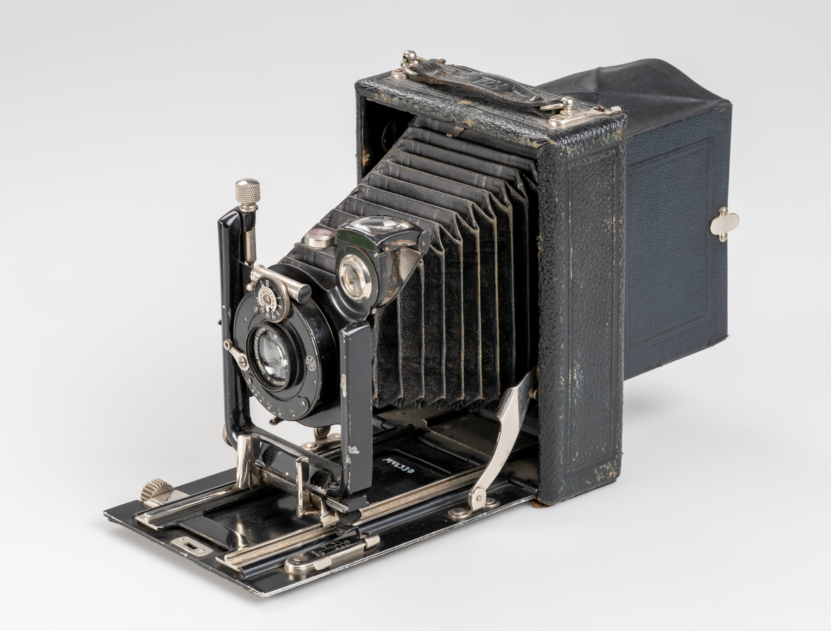 Utdragbar kamera av bälgmodell av tyskt fabrikat, märke AGC "FIX" ca 1935. Avsedd för glasplåtar eller cellulloidfilm, storlek 9 x 12 cm. Förvaras i en svart läderväska med axelrem. I väskan finns även fack för negativ etc. 

Kameran har använts till dokumenation på Smålands museum.