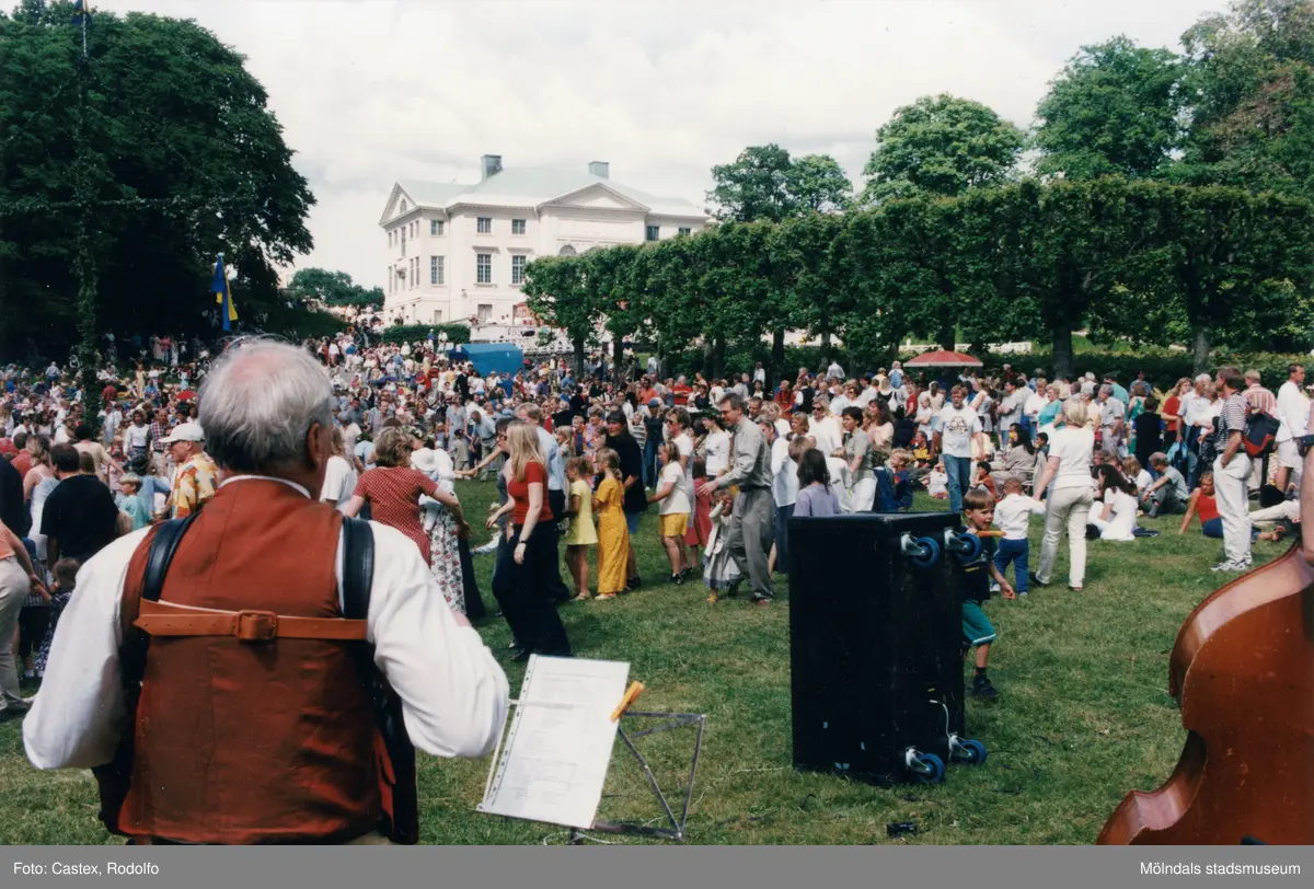 Midsommarfirande vid Gunnebo slott i Mölndal, okänt årtal. Dans kring midsommarstången. Slottet i bakgrunden.