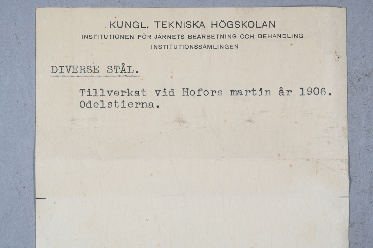 12 prover på stål. Alla prover märkta med Hofors M och sedan olika nummerföljder. Tre stycken är märkta med "010", en är märkt "020", två är märkt "030", två är märkt "040" och de andra tre proverna är märkt "050", "060" och "110". Tillhörande lappar med notering: "2721. Hofors martin 1906. O-A." och "Diverse stål. Tillverkat vid Hofors martin år 1906. Odelstierna."