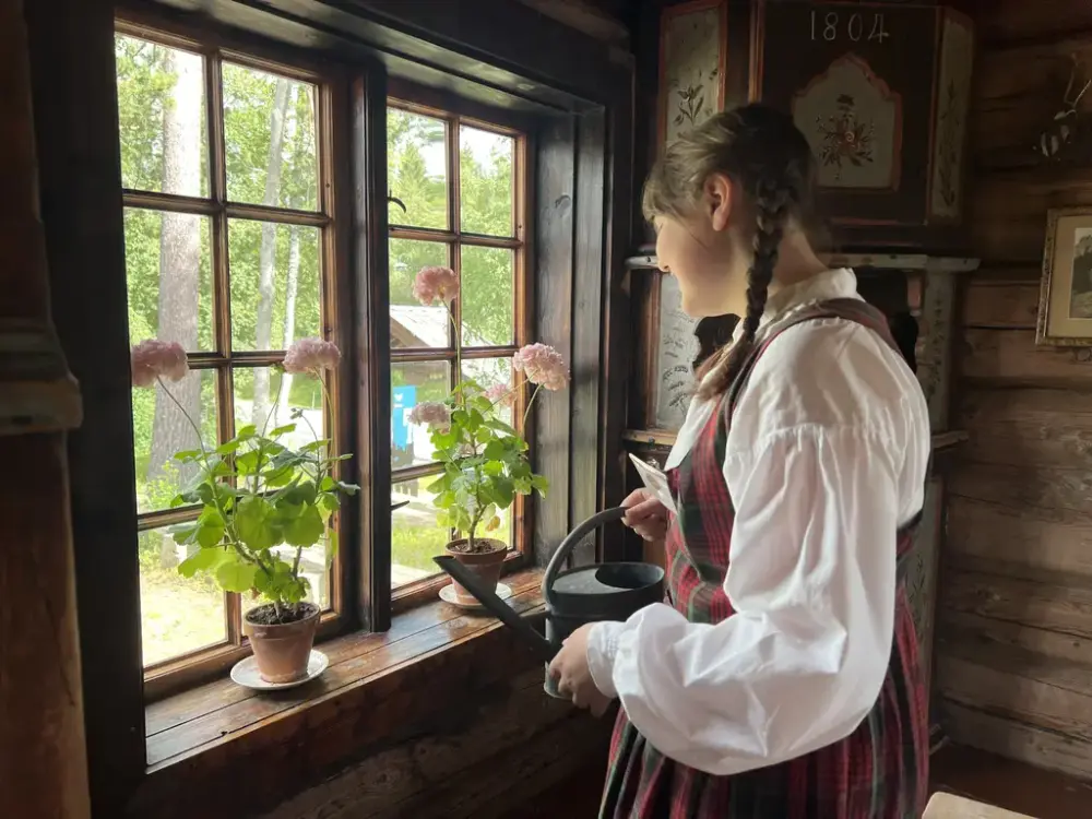 Jente som er kledd i stakk med vannkanne i handa