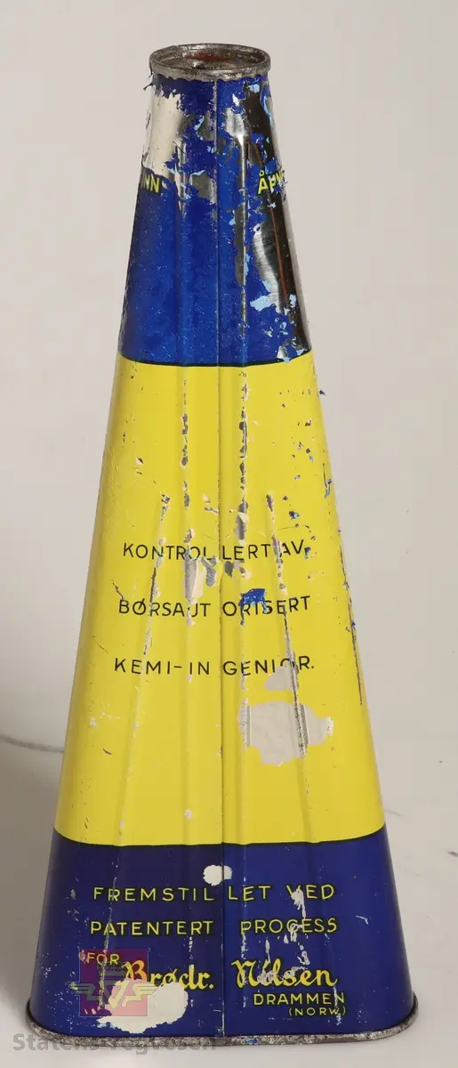 Pyramideformet, avrundet metallboks som er bredest i bunn og smaler inn til en rund tutform i toppen. Boksen er gul med blå skrift, med et blått felt øverst og nederst med gul skrift. 