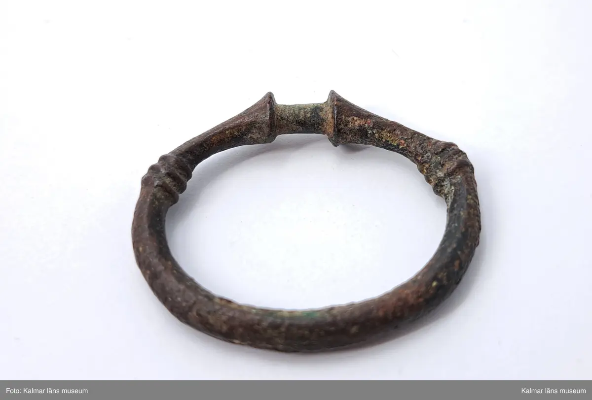 KLM 1202. Ringnål. Endast själva ringen som utgörs av en trind bronsten. Den är ornerad med två grupper av tre låga, tvärgående åsar.