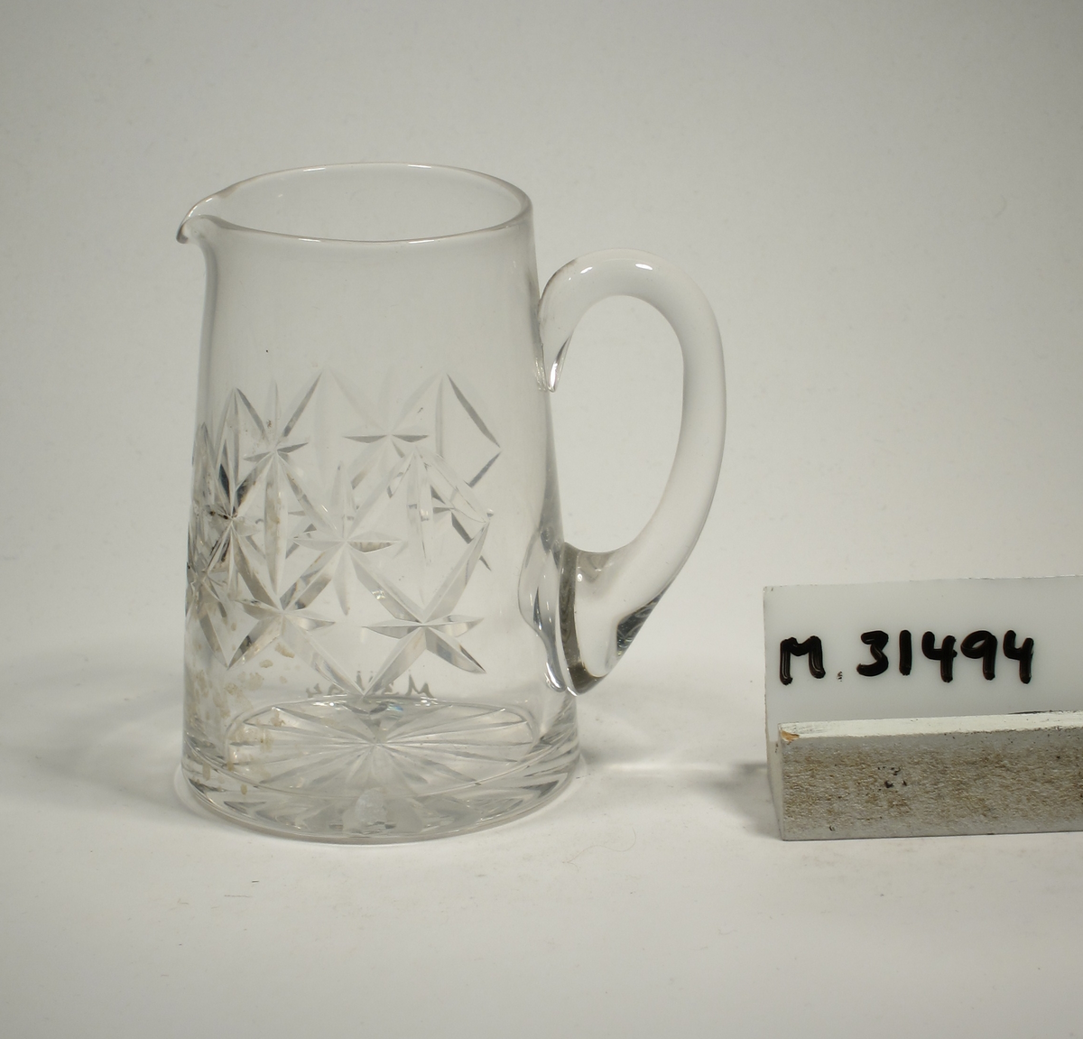 Konande form med skärslipat mönster runt kupan. Stjärna i botten. Påklippt grepe.