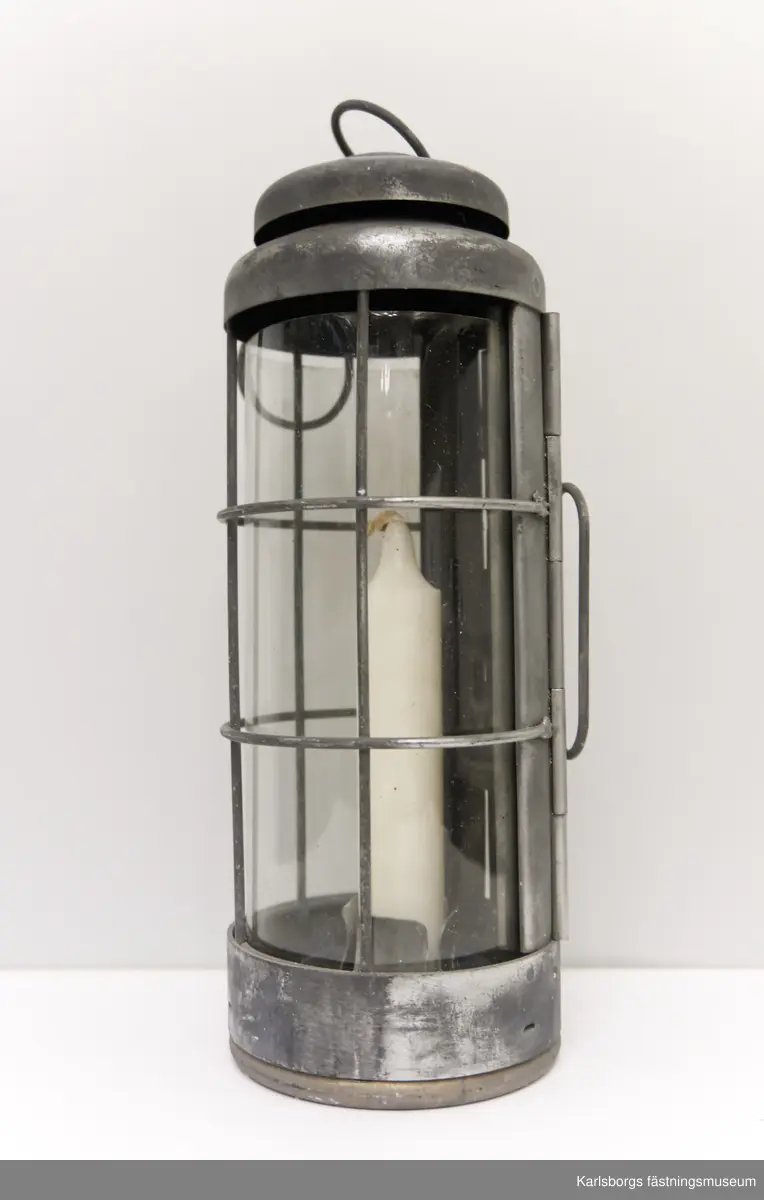 Handlykta fm/1940 för stearinljus med behållare vars lock saknas. Behållaren har fack, av metallskiva, för fyra stycken stearinljus. Själva lyktan består av metall och celluloidskiva. Celluloidskivan kan bytas ut mot en annan.