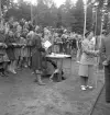 Folkskolans tävlingar, 1944.
Domarbord m.m. vid löparbanan. Bredvid bordet syns många barn, som hänger
på räcket.