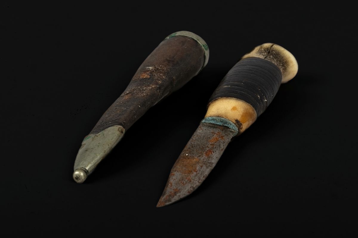 Kniv og slire. Kniven har skaft i bein som er slipt glatt. Rundt skaftet er det trukket skinn. Skinnet er surret rundt skaftet. Sliren består av metall (sølv) og skinn. På skinnet vises konturer av tidligere dekoreringsarbeid. Sømmen bak sliren er meget tett, bein og jevnt sydd. På slirens inngangsparti er det lagd et sølvbeslag som fungerer som en slags falsavslutning. Denne har dekor i form av to streker som går parallelet med lengdretningen av beslaget, altså på tvers av sliren. Den ene streken er nesten slitt bort. 
I tuppen av sliren er det festet et beslag av metall eller sølv. Dette er avsluttet med en liten kule, som utgjør tuppen av sliren.  Kniv og slire er forseggjort og er et pent arbeid.