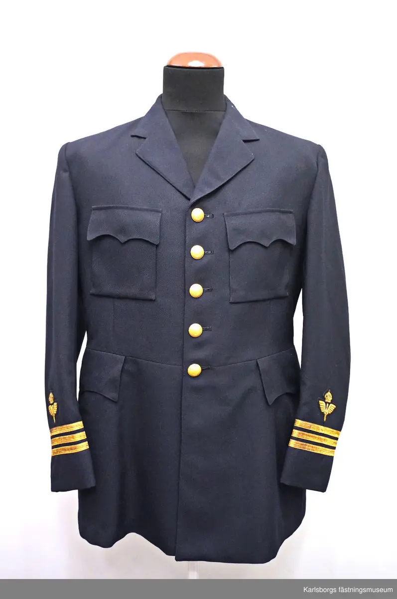 Vapenrock m/1930 är livskuren och enradig med fem uniformsknappar m/30. Den är försedd med skulder- och skörtsömmar, ryggslits, påstickade bröstfickor med enkel bälg och fasonerade ficklock samt foder av polyamidtrikå med två innerfickor och en pennficka samt en cigarettficka. Vapenrocken har insydda sidfickor med fasonerade ficklock, slag av enradig typ, men utan axelklaffar. Ärmarna är försedda med ett 70 mm flygemblem samt gradbeteckning kapten. Storlek: C104. Tillverkningsår: 1974.