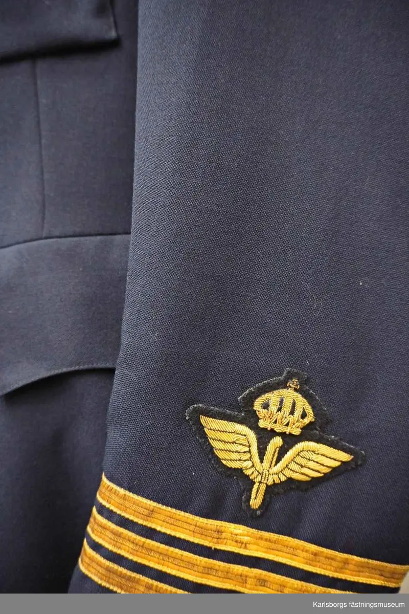 Vapenrock m/1930 är livskuren och enradig med fem uniformsknappar m/30. Den är försedd med skulder- och skörtsömmar, ryggslits, påstickade bröstfickor med enkel bälg och fasonerade ficklock samt foder av polyamidtrikå med två innerfickor och en pennficka samt en cigarettficka. Vapenrocken har insydda sidfickor med fasonerade ficklock, slag av enradig typ, men utan axelklaffar. Ärmarna är försedda med ett 70 mm flygemblem samt gradbeteckning kapten. Storlek: C104. Tillverkningsår: 1974.