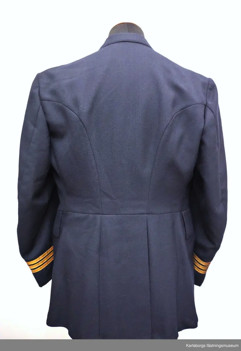 Vapenrock m/1930 är livskuren och enradig med fem uniformsknappar m/30. Den är försedd med skulder- och skörtsömmar, ryggslits, påstickade bröstfickor med enkel bälg och fasonerade ficklock samt foder av polyamidtrikå med två innerfickor och en pennficka samt en cigarettficka. Vapenrocken har insydda sidfickor med fasonerade ficklock, slag av enradig typ, men utan axelklaffar. Ärmarna är försedda med ett 70 mm flygemblem samt gradbeteckning kapten. Storlek: C104. Tillverkningsår: 1974.