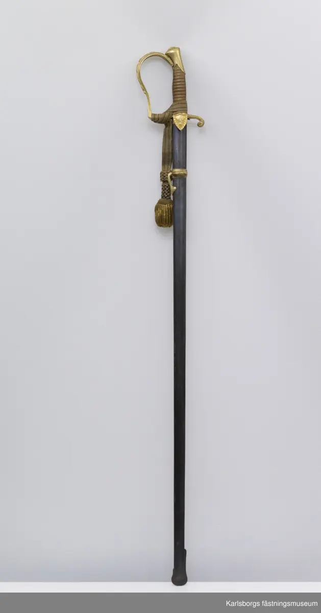 Sabel m/1889 (pallasch), tveeggad klinga med skålslipning på en längd av 71 cm. Total längd: 95cm. Klingans längd: 80cm. Klingans bredd: 3cm. Den yttre styrskenan är ciselerad i form av en sköld prydd med tre kronor. Baljan är av stål. Portepé m/1797, sabelhandrem i silke, medföljer.
