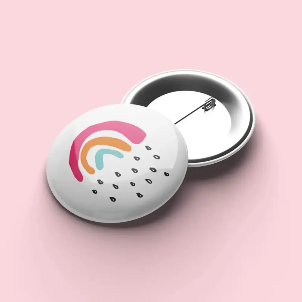 En hvit button med regn og en regnbue på en rosa bakgrunn.