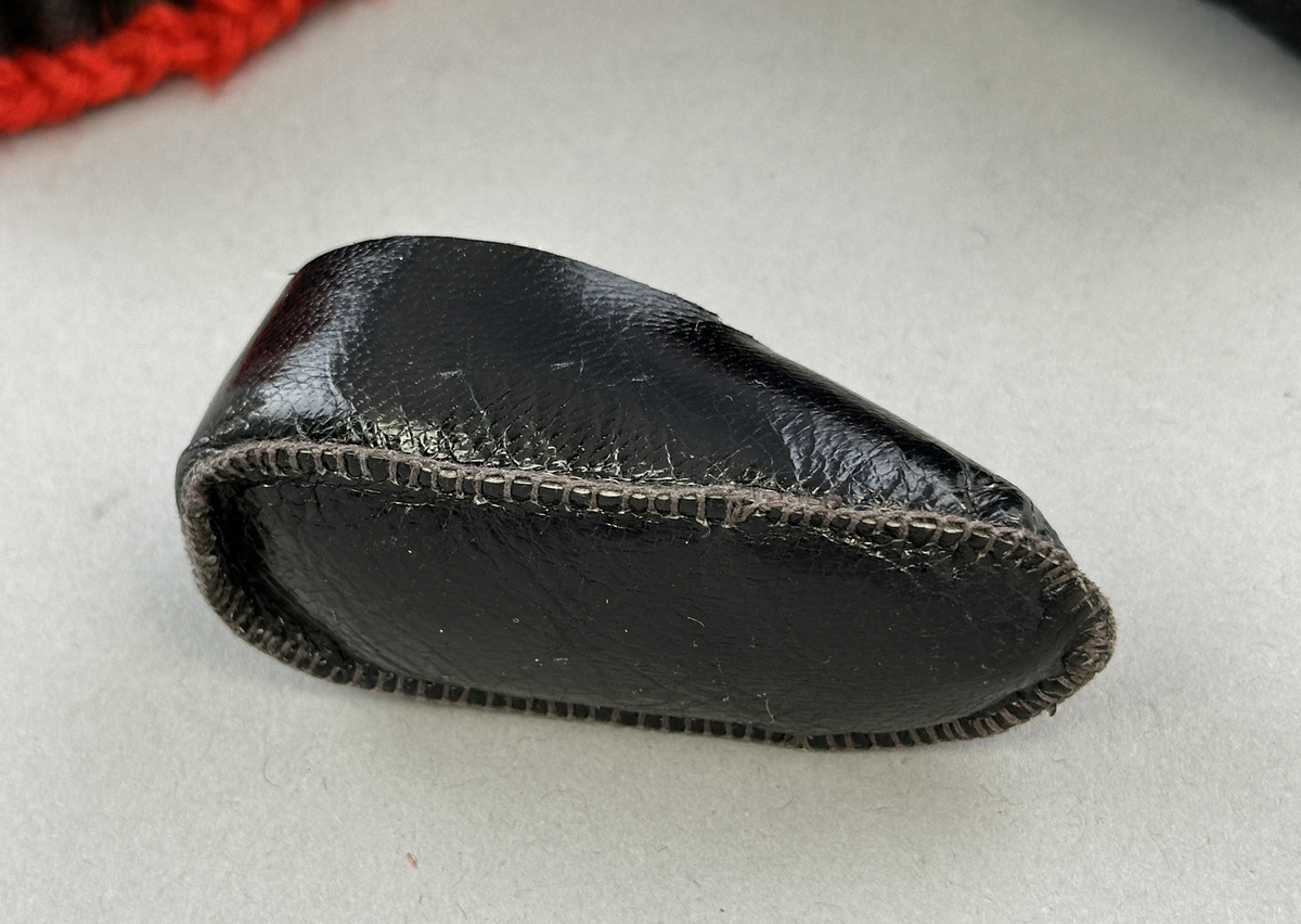 Docka klädd i kvinnlig sockendräkt från Norra Ny i Värmland. Kroppen är sydd i linnetyg och stoppad med textilt material. Huvud och händer är av lergods. Kläder sydda av handvävda tyger förutom skjorta, underkjol och halskläde, som är maskinvävt. Halskläde är broderat med tambursöm, skjortan med plattsöm och myrgång samt har stripade veck runt halskrage och manschetter. Även kjolen har lagda veck runtom och är fastsytt med livstycket. Förklädet, med 3 lagda veck på var sida, är kantad runtom med en tre-fläta gjord av rött ullgarn, vilket också kjolen har i nederkanten. Ullstrumporna är handstickade i slätstickning med en kant upptill i 2-2 resår och broderad med förstygn av rött ullgarn. Huvudet är prytt med hår av lintågor, som delvis är flätat till hårflätor samt ett målat hårnäver. Dockans fötter bär svarta skinnskor.
