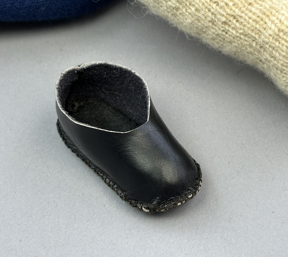 Docka klädd i kvinnlig sockendräkt från Ulleruds socken i Värmland. Kroppen är handsydd i linnetyg och stoppad med textilt material. Huvud och händer är av lergods. Kläder handsydda av handvävda tyger förutom skjorta, underkjol och halskläde, som är maskinvävt. Skjorta, broderad med myrgång runt sprund, har halsspjäll, halslinning och handlinning. Halsklädet, med tryck i gult, rosa och beige, hålls ihop av en sölja i nysilver med graverat mönster. Kjol sydd med lagda veck runtom, utom under förkläde, vars linning består av ett bomullsband. Förkläde, vävt i tuskaft och munkabälte, har lagda veck vid midja och bomullsband i rips till knytband. Livstycket är vändsytt/fodrat med ett rutigt bomullstyg och knäpps med 6 hyskar & hakar. Ullstrumporna är handstickade i slätstickning med en kant upptill i 2-2 resår. Huvudet är prytt med en vit linnehätta kantad med en knypplad linnespets. Dockans fötter bär svarta skinnskor.
