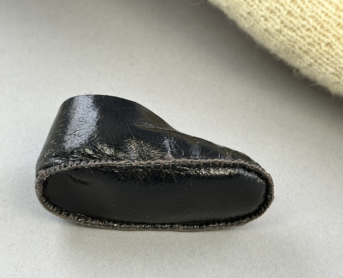Docka klädd i kvinnlig sockendräkt från Sunne socken i Värmland. Kroppen är handsydd i linnetyg och stoppad med textilt material. Huvud och händer är av lergods. Kläder handsydda av handvävda tyger förutom skjorta, underkjol och halskläde, som är maskinvävt. Skjorta, broderad med stopphålsömsbroderi i vitt lingarn längs sprund mitt fram, har stripade veck runt krage och manschett. Halskläde, broderad med tambursöm i vitt moulinegarn, hålls ihop av en sölja i nysilver med graverat mönster. Yllekjol är rynkad upptill, utom under förkläde, vars linning och skoningsband består av ett bomullsband. Förklädet har lagda veck vid midja fastsydda mot en linning av bomullsband. Livstycket med sköld i ylletyg, är vändsytt/fodrat med ett mönstrat bomullstyg och knäpps med 5 hyskar & hakar samt har 2 små tennknappar fastsydda på utsidan. Ullstrumporna är handstickade i slätstickning med en kant upptill i 2-2 resår. Huvudet är prytt med en vit linnehätta kantad med en knypplad linnespets. Dockans fötter bär svarta skinnskor.