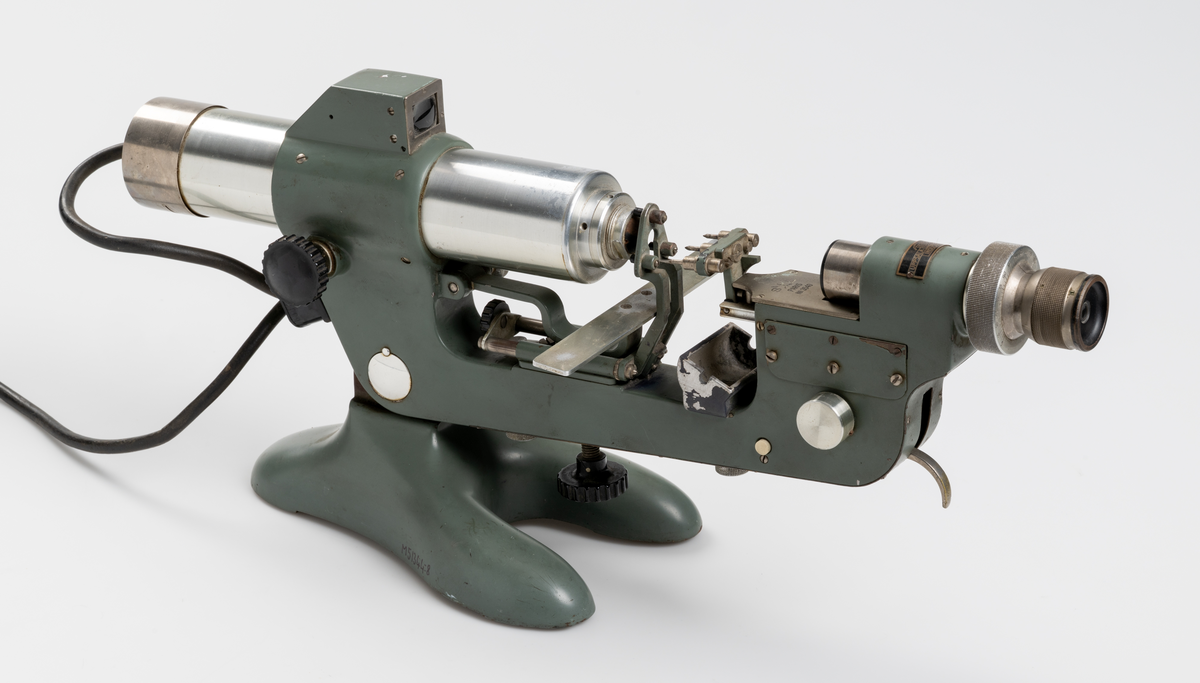 Vertometer, optiskt instrument för analys av linser, tillverkad av gjutjärn, stål, aluminium och glas. Grönlackerad. Dyna för märkfärg saknas.
Såld av Uppsala Optiska Industri AB.