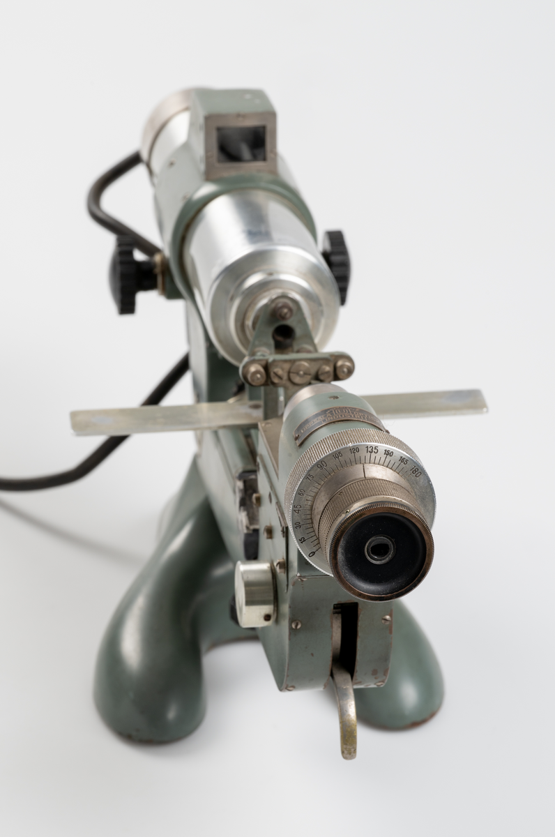 Vertometer, optiskt instrument för analys av linser, tillverkad av gjutjärn, stål, aluminium och glas. Grönlackerad. Dyna för märkfärg saknas.
Såld av Uppsala Optiska Industri AB.