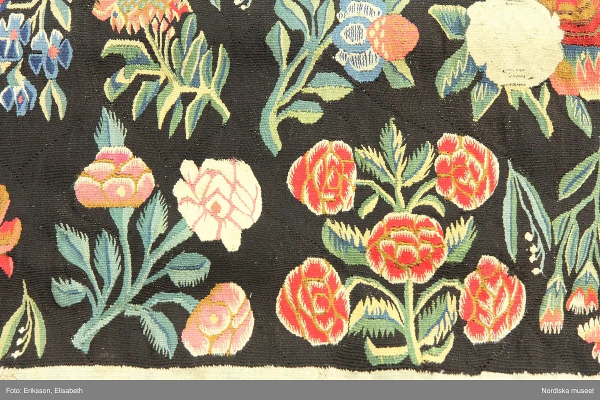 Huvudliggaren:
"Vävd tapet från 1700-talets början. Enligt uppgift från Skåne. Framställer varjehanda blommor strödda mot svart grund."
