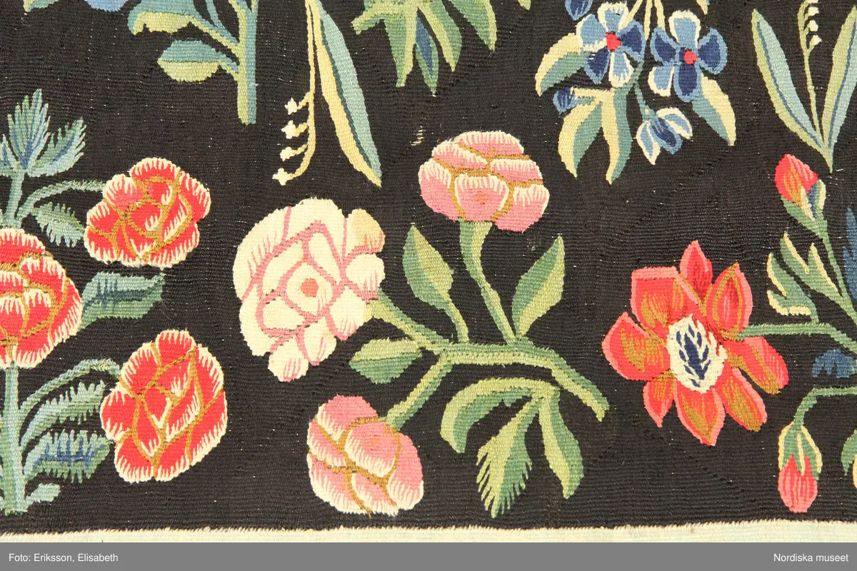 Huvudliggaren:
"Vävd tapet från 1700-talets början. Enligt uppgift från Skåne. Framställer varjehanda blommor strödda mot svart grund."
