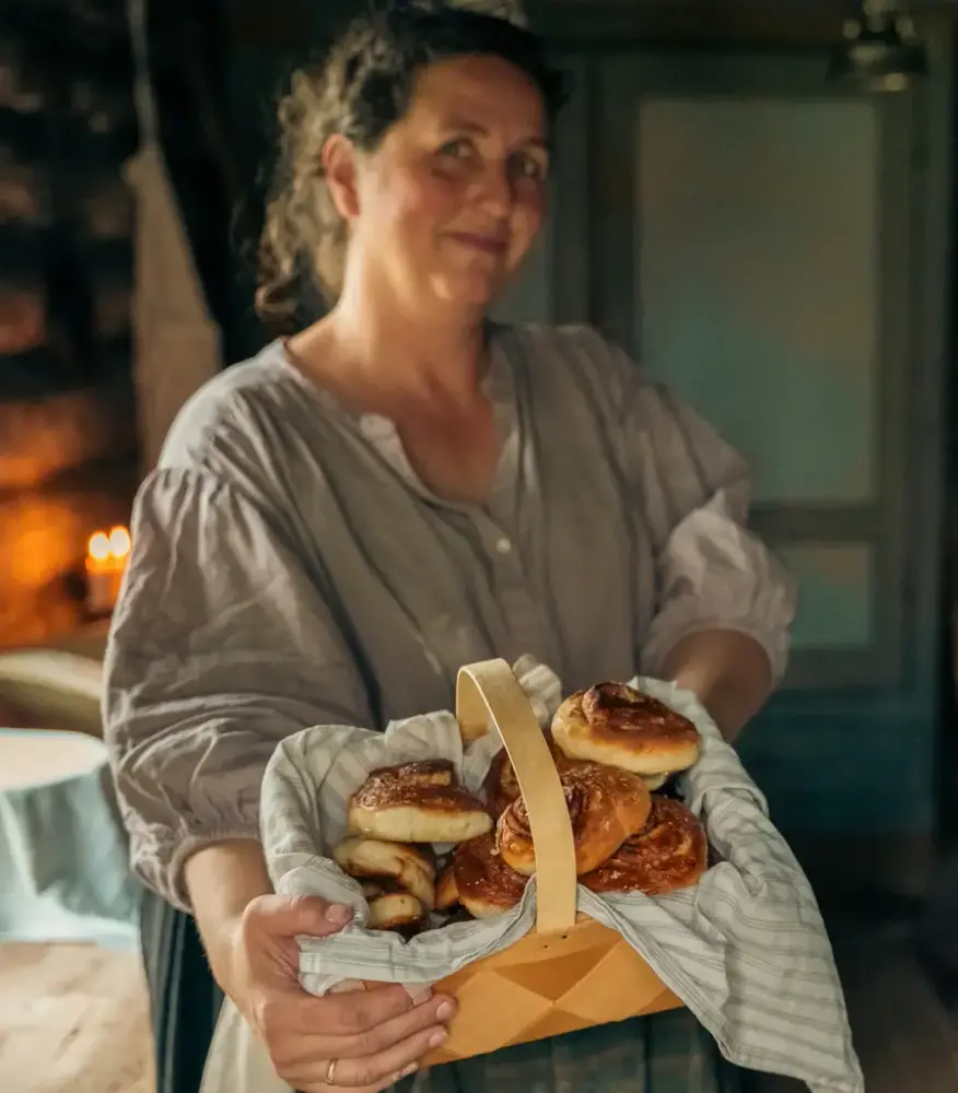 Smilende dame med nybakte kanelboller i en kurv