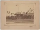 Gymnastikfest 1891. Man gör honnör vid bord med idrottspriser. Militärer i närheten hedrar kunglig paviljong.