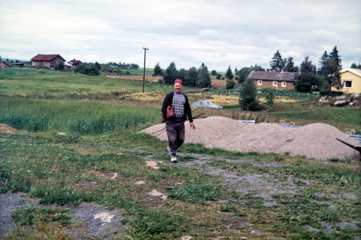 Ottar Myhre (1914-1973) på veg hjem etter endt arbeidsdag. Bak til venstre ligger småbruket Sangen.  Det gule huset har navnet Solbakken. Og bakerst til høyre ligger småbruket Hagelund. Begge de to siste har adresse langs Hagelundvegen i Ottestad.