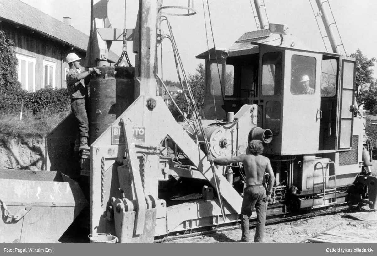 Pillarene til Sandesundbrua i Tune, under bygging 1973. Persone er ukjente. Brua var under bygging i 1970-78,  og ble åpnet i 1978. Sandesund bru ble en del av Europavei 6 i Østfold i 1978, da den sto ferdigbygget. Den hadde da to kjørefelt og gikk fra Alvim til Årum.
