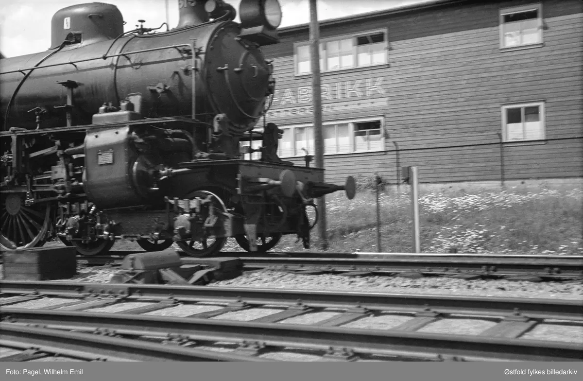 Tog passerer lokalene til Grei Divanfabrikk i Tune like ved Sandesund jernbanestasjon. Fabrikken flyttet inn i disse lokalene fra 1937.
Lokomotivet på bildet - et svensk SJ littera B - ble innleid av NSB til Østfoldbanen i 1936-37.