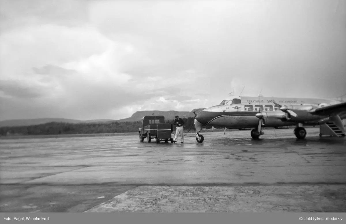 Passasjerfly på ukjent rullebane, operatør Braathens SAFE. Flyet er av typen De Havilland DH 114 Heron. Det blir fylt bensin.