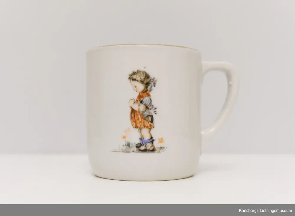 Kaffekopp med barnmotiv och fjäril. Guldmönstrad kantbård. Märkt på undersidan av tillverkarna men är svårläst.