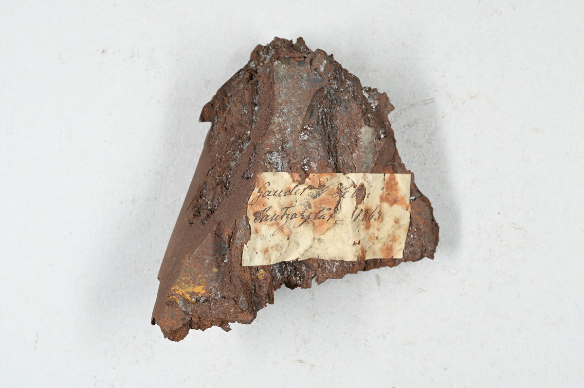 Prov på pansarplåt. Märkning på provet med påklistrad lapp med notering: "Gauder & Petin (?) pantzarplåt, 1863." Två tillhörande lappar med notering: "2119. Bit av pansarplåt från Petin & Grandet år 1863. Har givit 0,8% slagg o.d. E. A. Dufva. 1864."