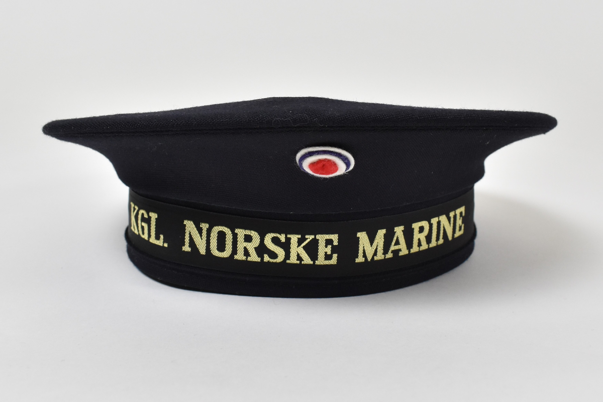 Svart rund lue som er flat på toppen og har eit band til å festa rundt haka.