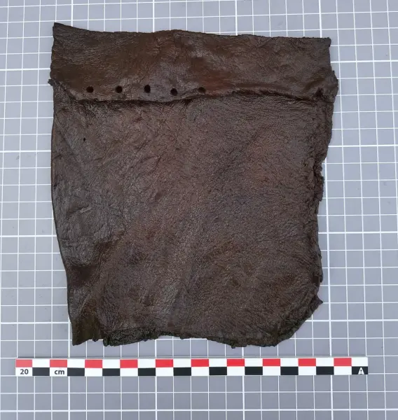 Rektangulært lærstykke med hull langs toppen, funnet under utgravning i Oslo.