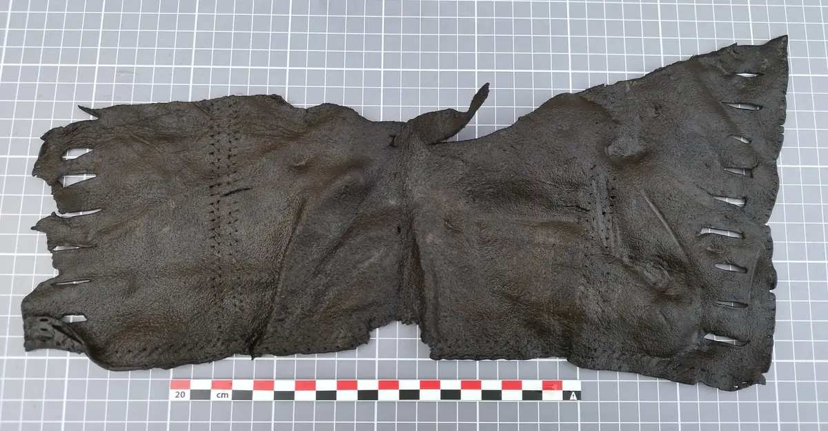  Stykke lær med sømmer og snitt for snøring, trolig del av en middelalderveske.