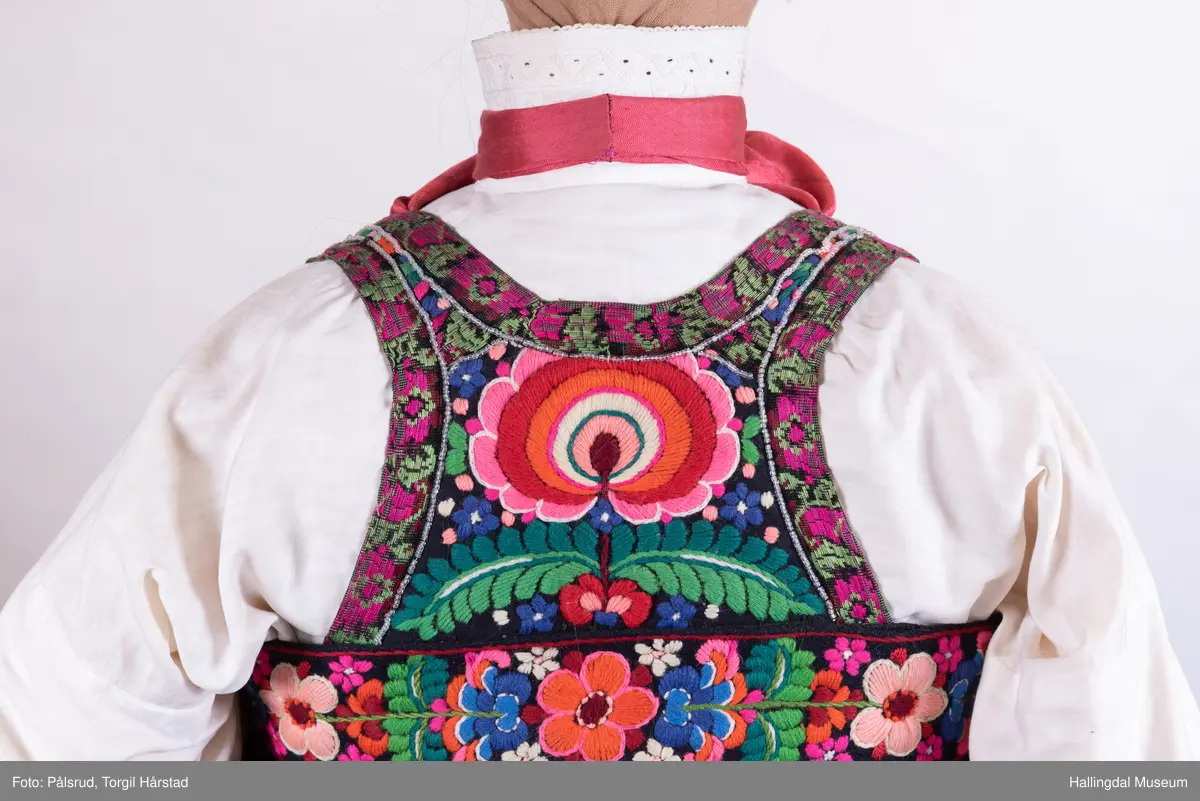 Kone frå Øvre Hallingdal, kyrkjekledd. Viser korleis gifte kvinner kunne gå kledd i Øvre Hallingdal. 

Truleg frå tidleg 1900-tal. Døs i svart ull, med brodert overliv i plattsaum og plattsaumbroderi nedst. forkle i svart ulldamask med plattsaumbroderi nedst. Døsa og forkle er truleg sauma av Birgit Anfinset (f. 1863). Sauma band kom nedanfrå dalen sist på 1800-talet, fyrst som forkleband. Banda var breiast rundt 1920, og denne stakken er truleg frå denne tida.

Hovudbunaden kallast hettepannelin eller lykkjeplagg (Ål), og er hovudbunaden til gifte. Her har silkeplagget (hettepannelinet) vorte stort og ferdigsydd. Storleiken på hettepannelinet har variert frå tid til anna.

Kona står utstilt i den faste bunadsutstillinga på Hol Bygdemuseum. 