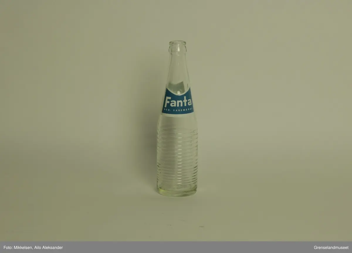 Gjenstanden er en brusflasker i glass med logo og varemerke til Fanta reg. varemerke. Flasken er hel og i god stand. Merkelappen er i god stand og viser bare tegn til å ha stått lagret over lengre tid. 