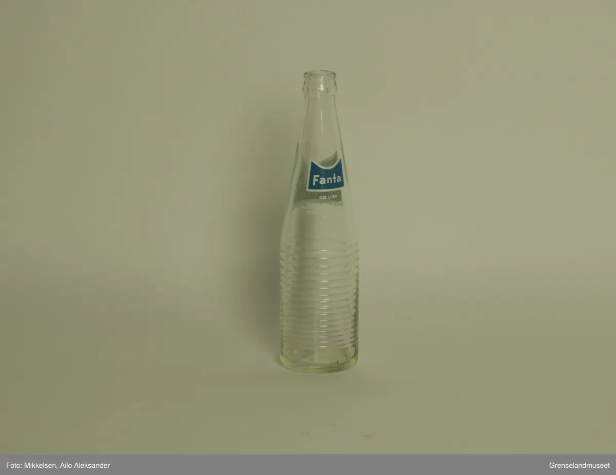 Gjenstanden er en brusflasker i glass med logo og varemerke til Fanta reg. varemerke. Flasken er hel og i god stand. Merkelappen er i god stand og viser bare tegn til å ha stått lagret over lengre tid. 