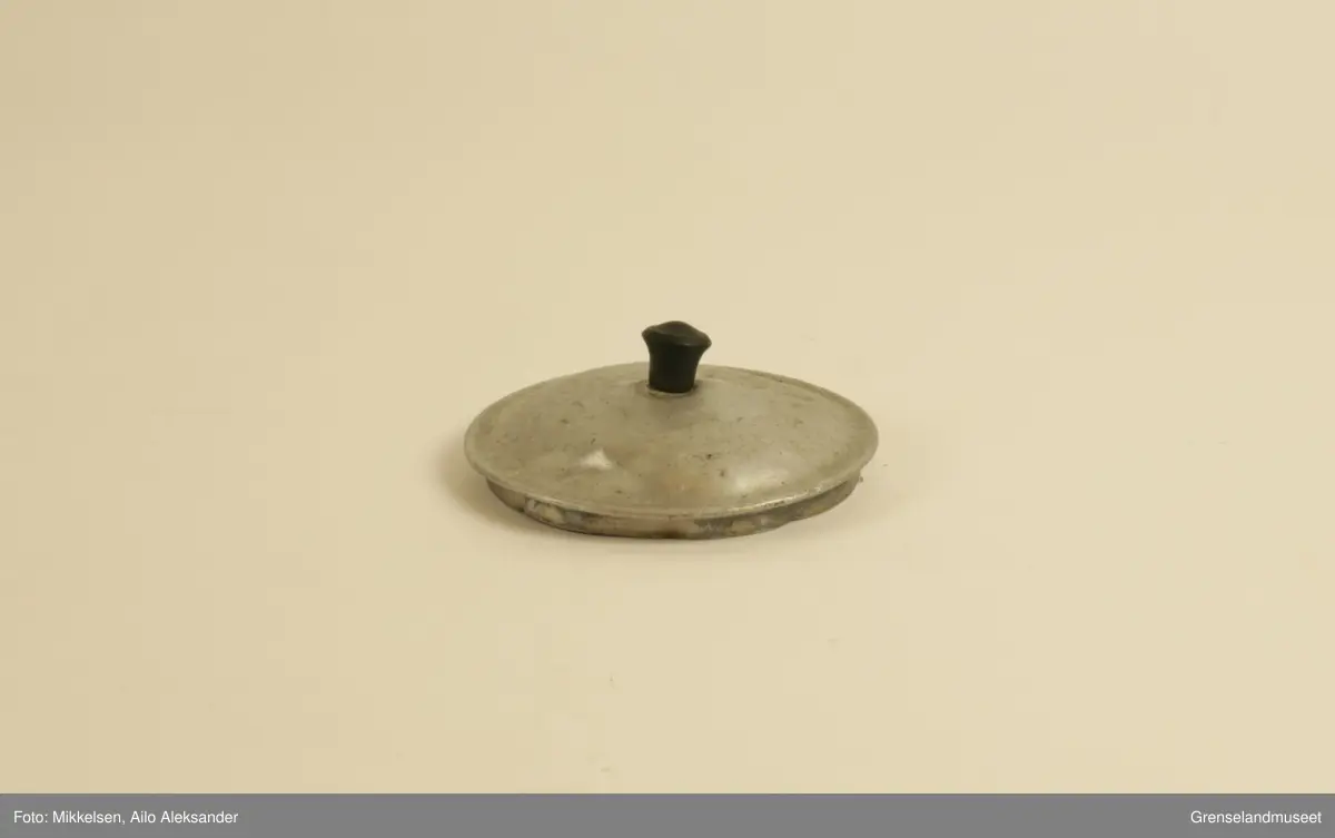 Gjenstanden er stor kaffekjele i jern, med original lokk og hanke medbrakt. Kaffekjelens innside viser at den har vært godt brukt med brunsvidde flekker fra kaffekoking. Utsiden er er jern grå, men undersiden har lag med svart svidd sot og rester. Det er en liten ripe på kjelens venstre side når man holder den i handtak. Ripen er ikke stor eller omfattende, men har fått litt rust som dekker det eksponerte underlaget av jern. Handtaket er jerngrått som resten av gjenstanden, men har med tiden fått et brunt fargeskjær på seg.         