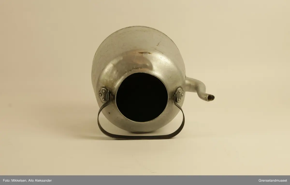 Gjenstanden er stor kaffekjele i jern, med original lokk og hanke medbrakt. Kaffekjelens innside viser at den har vært godt brukt med brunsvidde flekker fra kaffekoking. Utsiden er er jern grå, men undersiden har lag med svart svidd sot og rester. Det er en liten ripe på kjelens venstre side når man holder den i handtak. Ripen er ikke stor eller omfattende, men har fått litt rust som dekker det eksponerte underlaget av jern. Handtaket er jerngrått som resten av gjenstanden, men har med tiden fått et brunt fargeskjær på seg.         