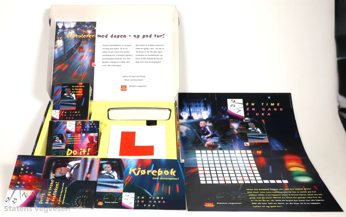 Pappeske som innholder opplæringsmateriell:
-Kjørebok
-Guide for øvelseskjøring
-Timeplan
-Video og CD
-"L" for å sette bak på bil
-Ekstra speil for passasjer/ledsager