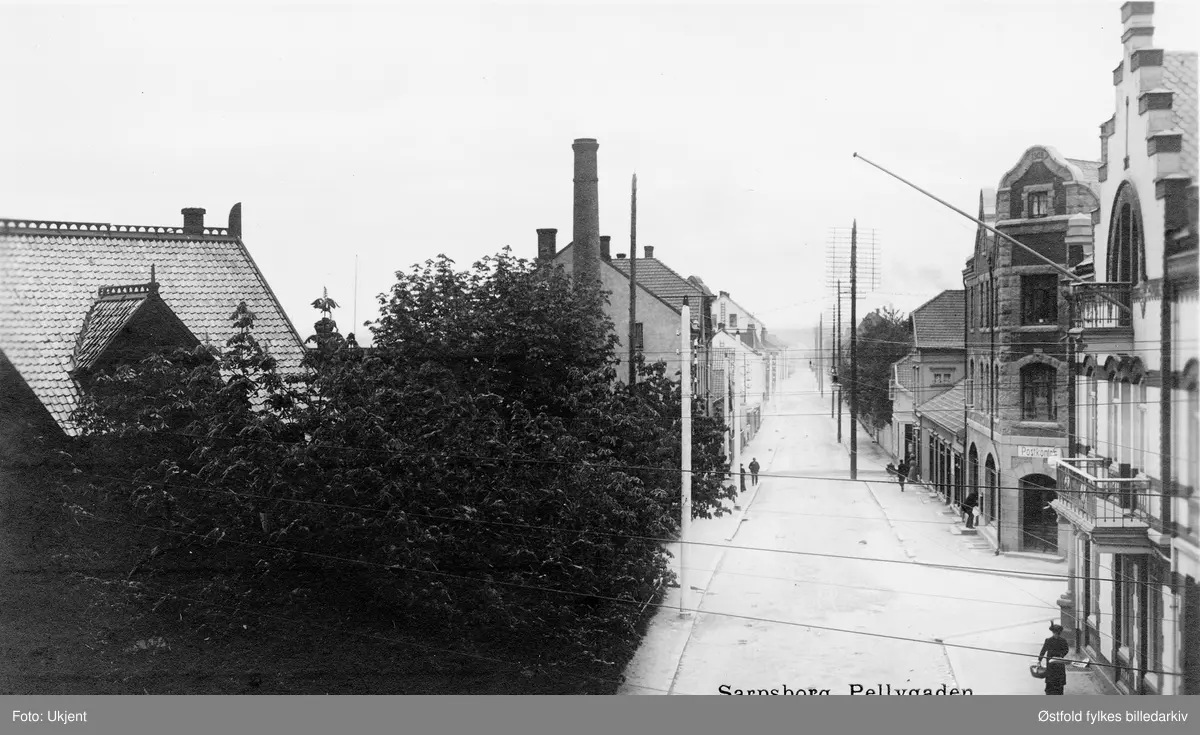 Pellygata i Sarpsborg sentrum, fra Torggata og østover og Haralds plass 1916.
Til høyre Asbjørnsen Bygg & Rør. Til venstre dr. Løkens hus i Torggata 6, skjult av tre. (Tidl. Dr. Lexows hus.) Postkort.