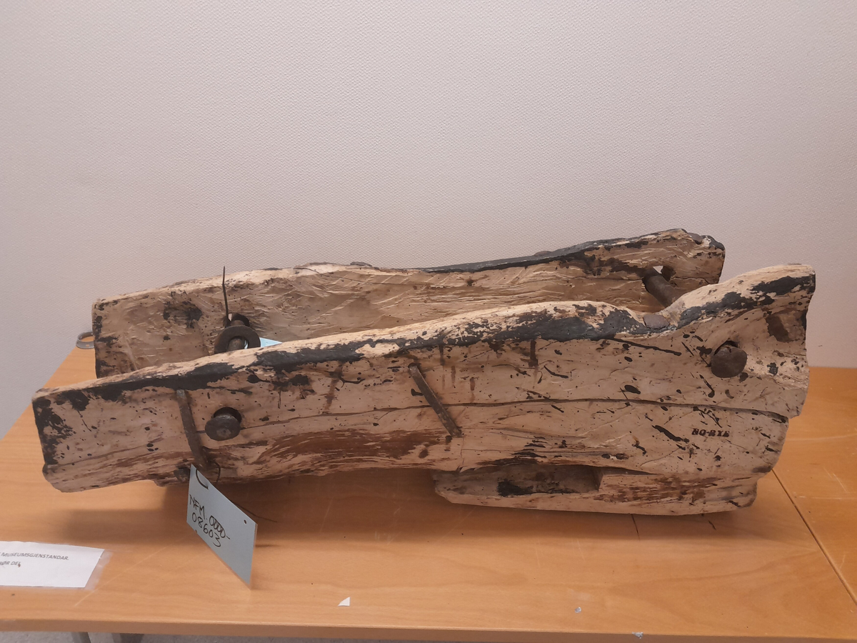 Renne i tre. Utholing truleg øksa ut.  Bolt i jarn gjennom to parallelle hol i sidene, oppe og nede. Boltane kan løysast og låsast. Jarn klammer og bolter (firekanta og runde hovud) er slått inn fleire stader i treet. Rektangulært hol i treet opp mot eine bolten. Områder med svart, truleg tjære.

Kan ha vore brukt på Holvikejekta som vern på baugen.