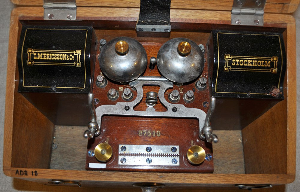 Telefonapparat. Använd vid 1896 års Andréexpeditionen. Till kommunikation mellan ballonghus och gasverk. Alternativt mellan marknivå och ballonggondol vid fast ballong. Rektangulär trälåda med handtag innehållande en telefon. Lös del i form av en tratt som ligger i lådan. Modellnamn: Nr. 87510.