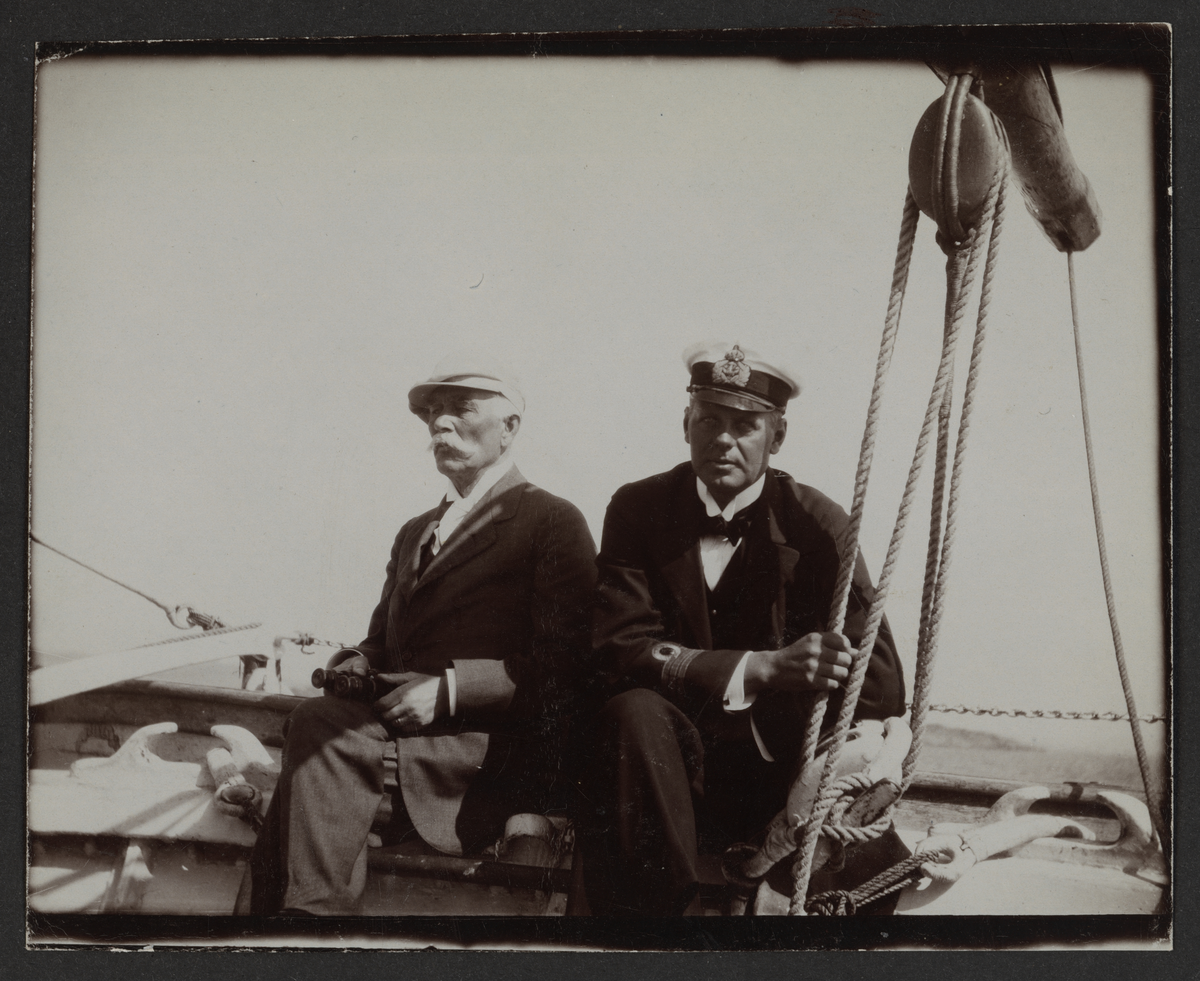 Bilden visar Wilhelm von Schoultz i kaptensuniform och en äldre man som seglar i en skeppsbåt.