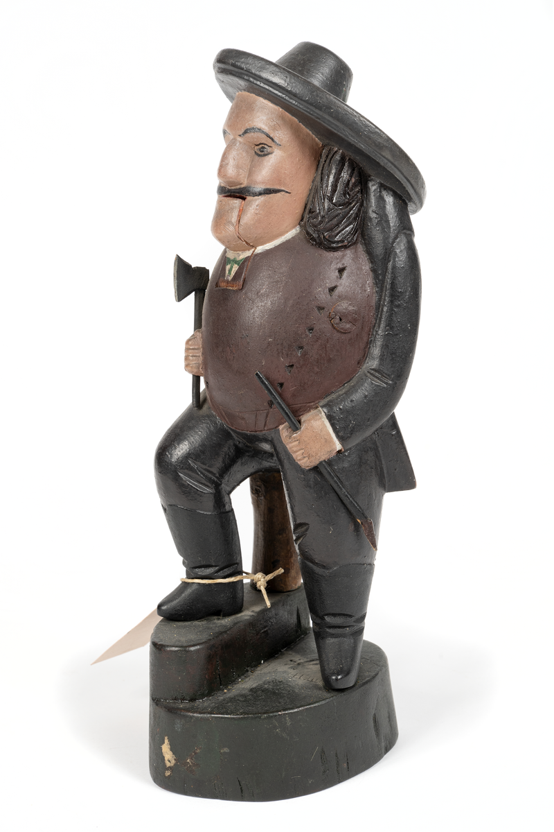 Träskulptur, (ungersk?) jägare med ledbar haka. I högra handen yxa, i vänstra bössa med avbruten kolv.