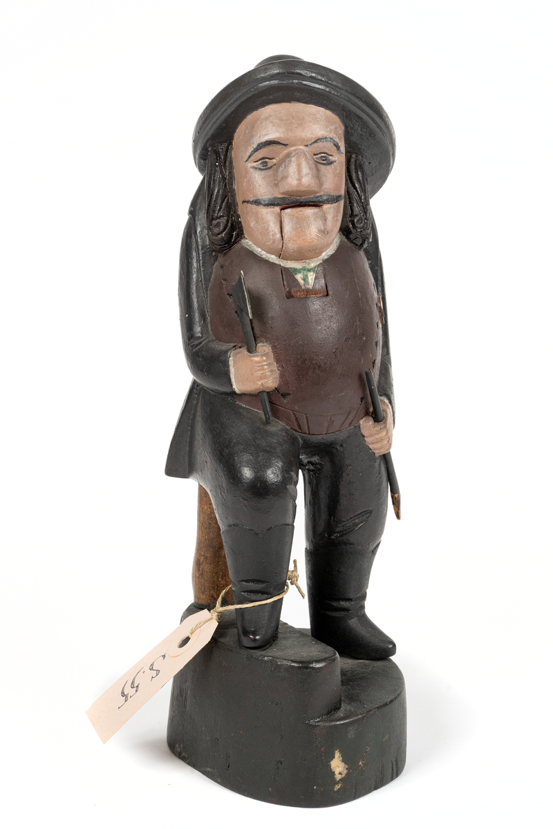 Träskulptur, (ungersk?) jägare med ledbar haka. I högra handen yxa, i vänstra bössa med avbruten kolv.