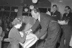 Hantverkstävling på Rotundan den 2 april 1950. Troligen prisutdelning. En kvinna mottar en filt/pläd av mannen till höger.