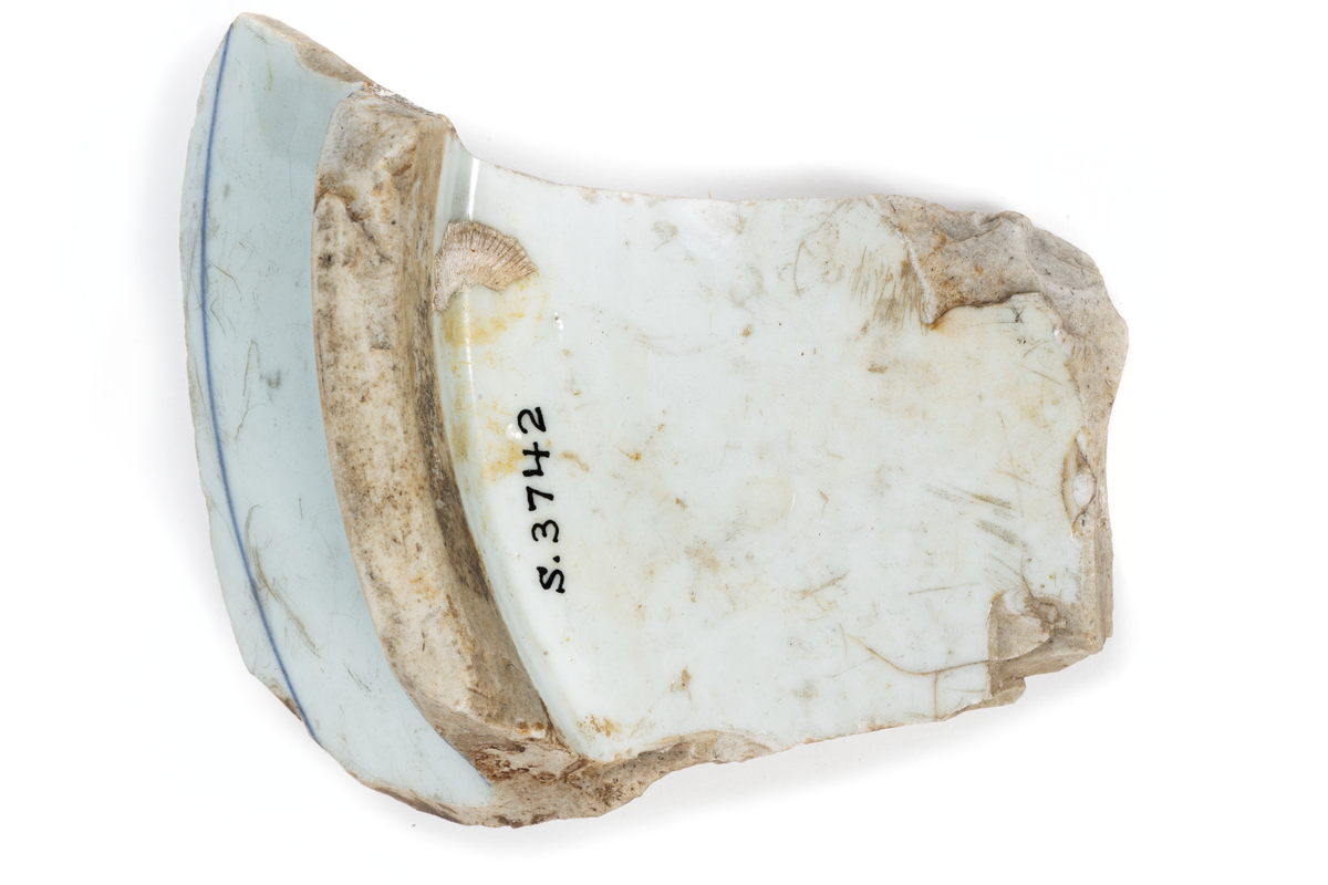 Fragment (skärvor) av ostindiskt porslin, vit botten, blå och brun dekor. Antal bitar= 111 st.