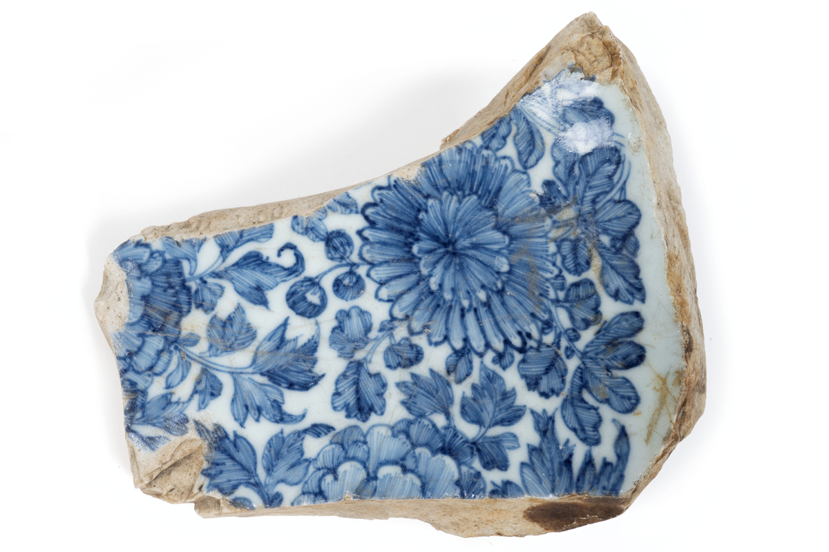 Fragment (skärvor) av ostindiskt porslin, vit botten, blå och brun dekor. Antal bitar= 111 st.