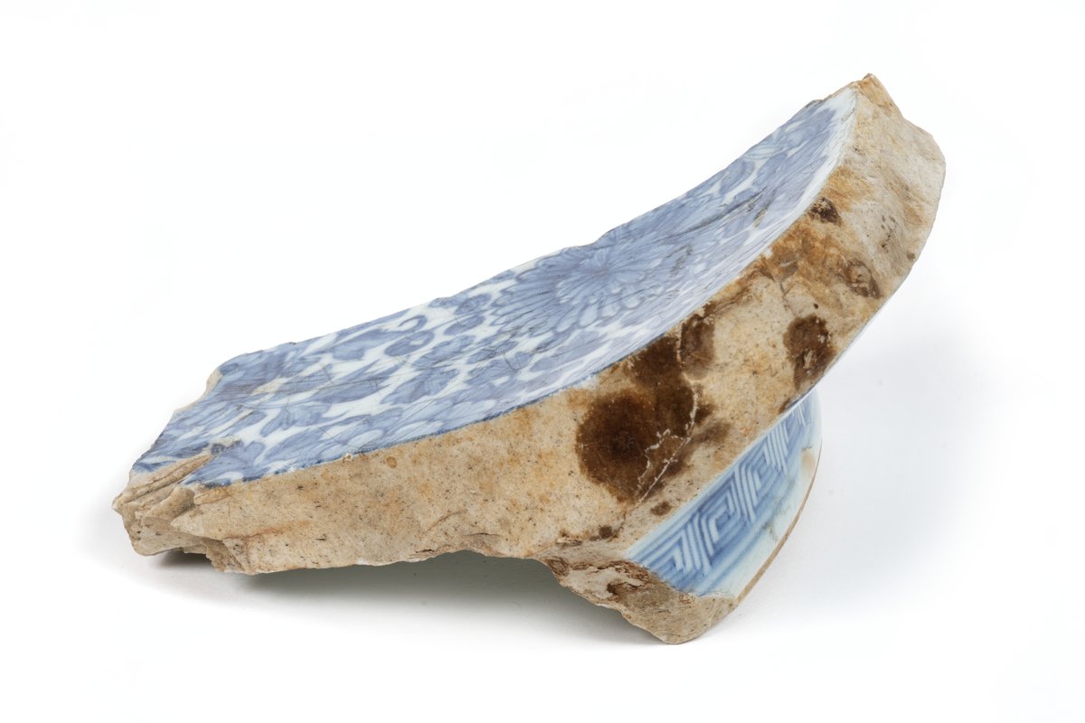 Fragment (skärvor) av ostindiskt porslin, vit botten, blå och brun dekor. Antal bitar= 111 st.