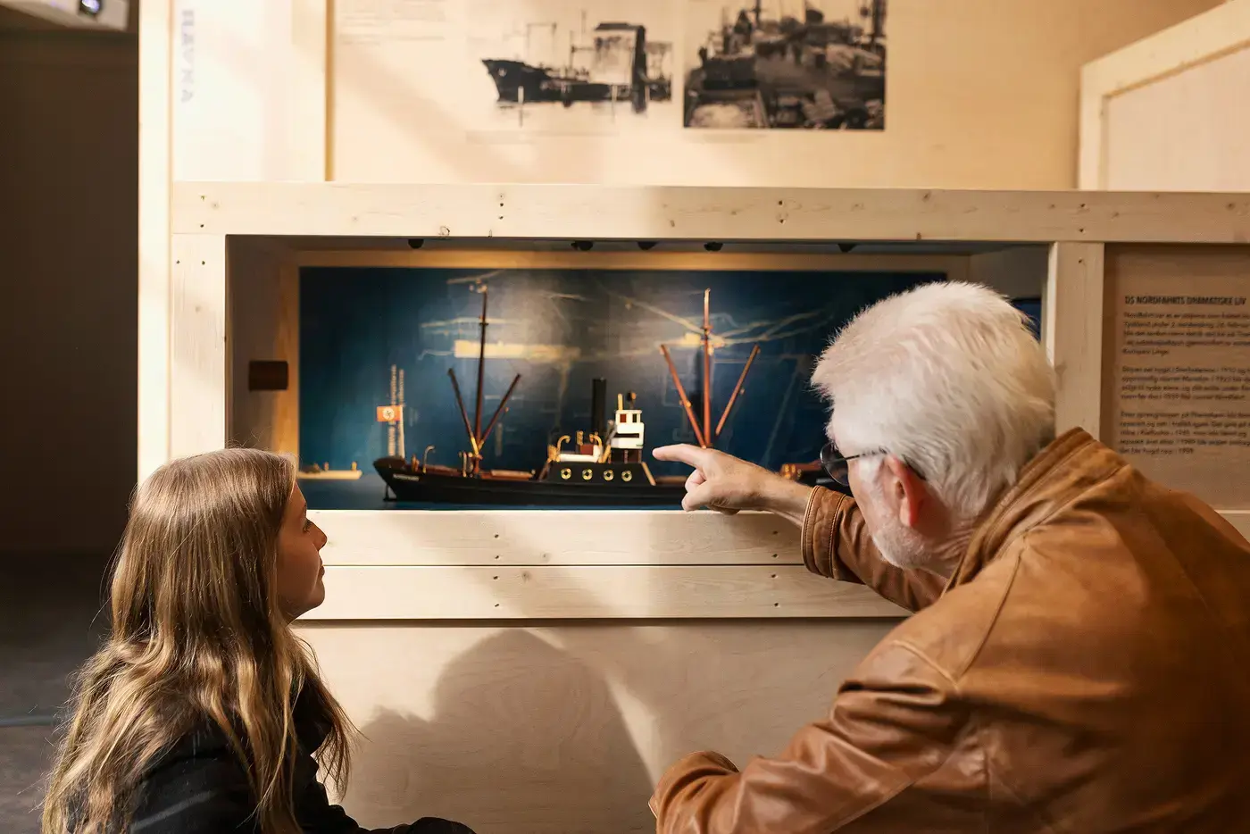 Voksen og barn ser i utstillingen Ut i verden